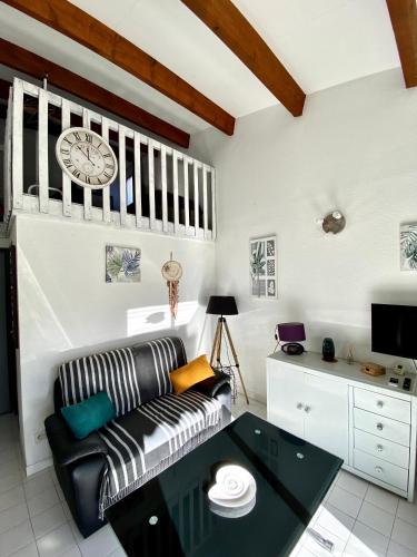 un salon avec un canapé et une horloge au mur dans l'établissement Maison de vacances parking wifi résidence calme Cap d Agde, au Cap d'Agde