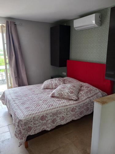 - une chambre avec un lit doté d'une tête de lit rouge dans l'établissement STUDIO chez La Maison Forte, à Montaut