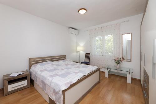 a white bedroom with a bed and a window at Apartman Angelina in Supetar
