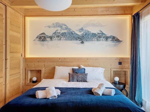 une chambre avec un grand lit avec une couverture bleue dans l'établissement Chalet SKADI, à Essert-Romand