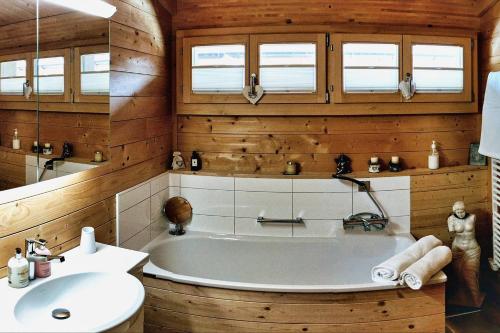 un bagno con vasca e lavandino di Cozy Scenic Family Chalet Gstaad Glacier 3000 a Gsteig