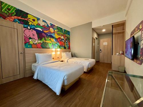 two beds in a room with a painting on the wall at MAXONE Dumai in Dumai