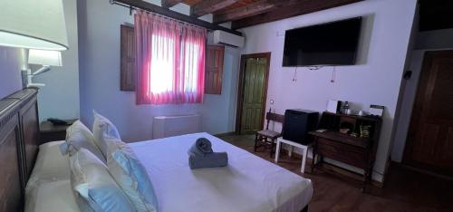a bedroom with a white bed and a television at Hospedium Hotel Rural Abadía de Yuste in Cuacos de Yuste