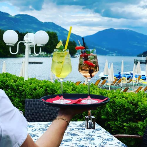 a person holding a tray with two glasses on it at Seehotel Steiner in Seeboden