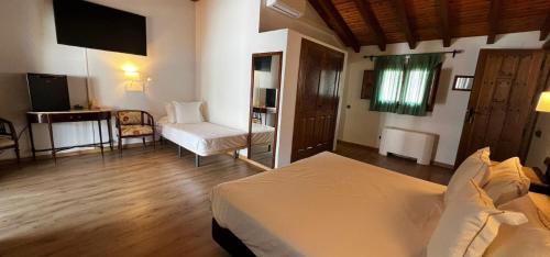 a bedroom with a bed and a chair and a television at Hospedium Hotel Rural Abadía de Yuste in Cuacos de Yuste