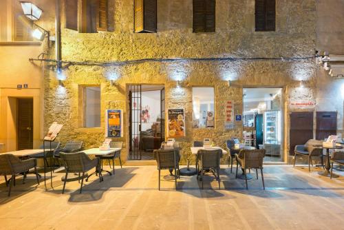 a restaurant with tables and chairs in front of a stone building at Hotel Can Simo in Alcudia