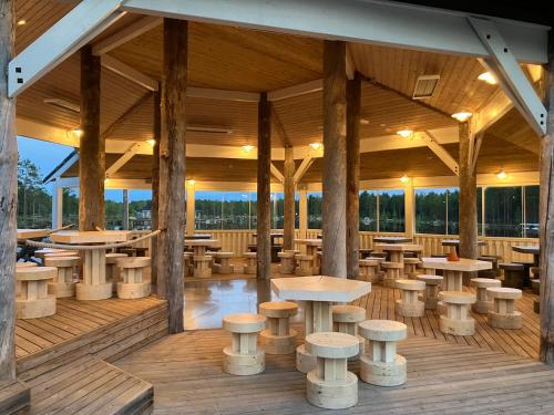 a restaurant with tables and stools on a wooden deck at HUNURIJÄRVI RESORT***** in Härmä