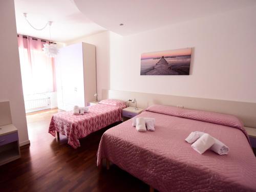 two beds in a hotel room with pink sheets at La Rosa dei Venti in Ortona