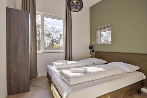 two beds in a room with two windows at Vakantiepark Leukermeer in Well