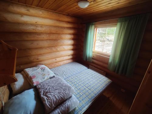 a small room with a bed in a log cabin at Kalliorinteen Mökit Havupirtti in Töysä