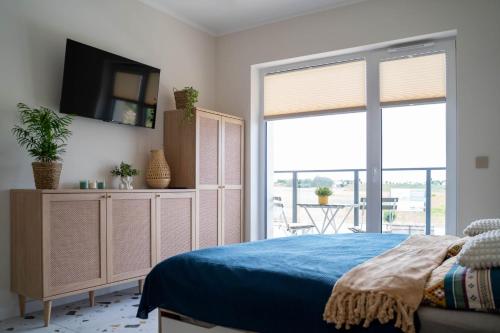 a bedroom with a bed and a tv and a window at Apartament Dla Ciebie III in Ustronie Morskie