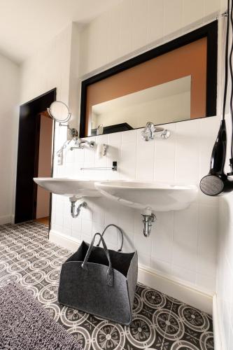 a bathroom with a sink and a bag on the floor at Design Hotel ALPENLIEBE - - - - Boutique-Flair - - - - in Inzell