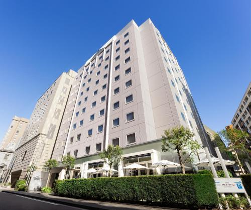 a white building with trees in front of a street at Hotel JAL City Kannai Yokohama in Yokohama