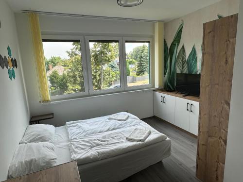 a small bedroom with a bed and two windows at Pauzo Balaton in Balatonföldvár