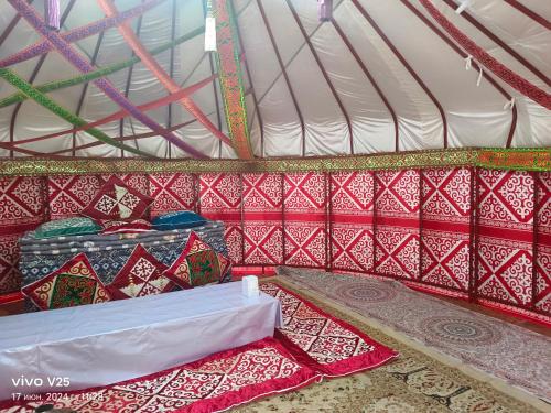 a tent with a table and pillows in it at Кольсайские озера, Юрта гостиницы Айару in Kurmenty