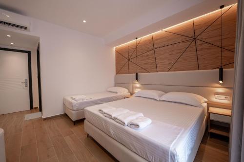 a bedroom with two beds with white sheets at ABOJA Inn in Ksamil