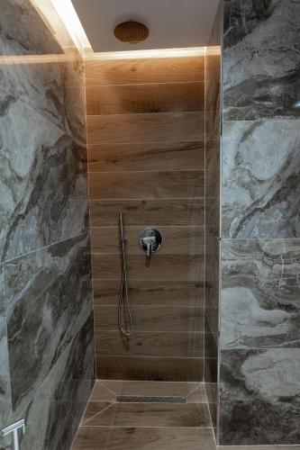 a shower in a bathroom with a stone wall at ABOJA Inn in Ksamil