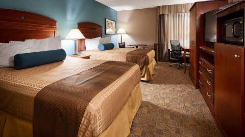 a hotel room with two beds and a television at Days Inn by Wyndham Englewood Dayton Airport in Dayton