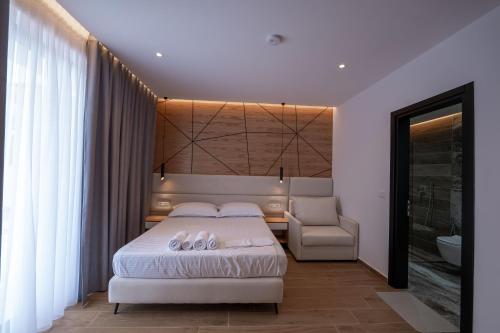 a bedroom with a king sized bed and a chair at ABOJA Inn in Ksamil
