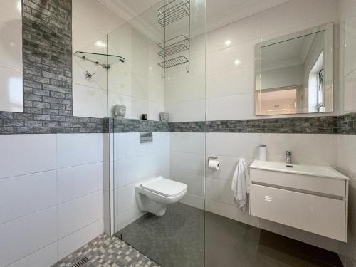 a white bathroom with a toilet and a sink at Vida Tranquilo in Edgemead