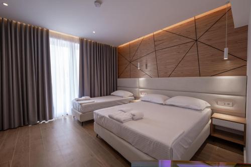 a bedroom with two beds and a large window at ABOJA Inn in Ksamil