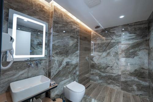 a bathroom with a toilet and a sink and a mirror at ABOJA Inn in Ksamil