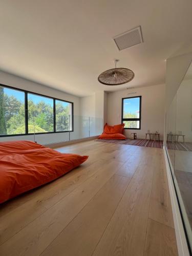 - une chambre avec un lit orange et de grandes fenêtres dans l'établissement Grande Maison familiale lumineuse avec piscine, à Luynes