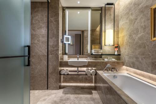 a bathroom with a tub and a sink and a mirror at Sofitel Singapore City Centre in Singapore