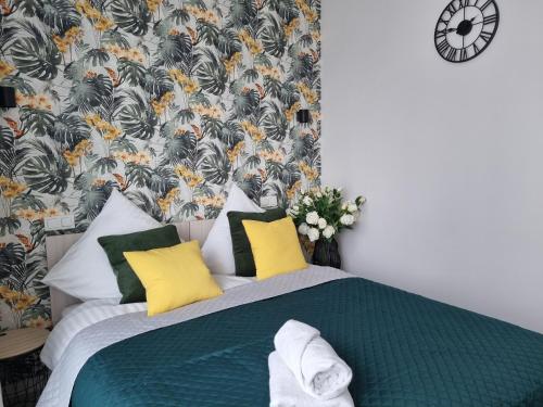a bedroom with a bed with yellow and green pillows at Q Apart Meta -1, 2 lub 3-pokojowe, klimatyzowane apartamenty przy Manufakturze z garażem lub parkingiem Gratis, FV in Łódź