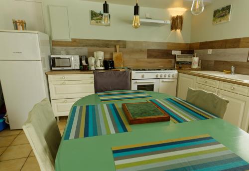 une cuisine avec une table et un réfrigérateur blanc dans l'établissement Le Logis Des Juliats, à Saint-Seurin-dʼUzet