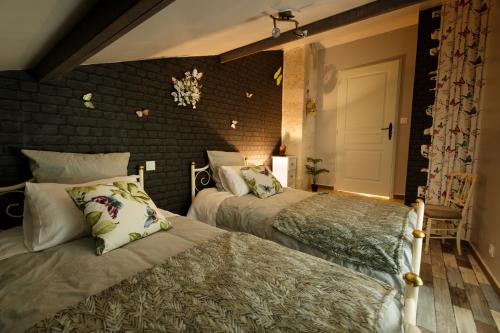 une chambre avec deux lits et un mur de briques dans l'établissement Le Logis Des Juliats, à Saint-Seurin-dʼUzet