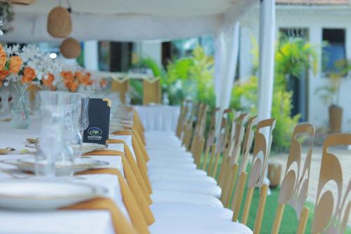 a long table with white tables and chairs at Mowicribs Hotel and Spa in Entebbe