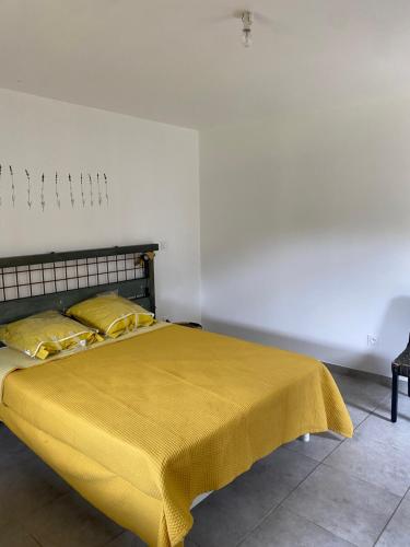 une chambre avec un lit avec une couverture jaune dessus dans l'établissement La Bergerie, à Saint-Rome-de-Cernon