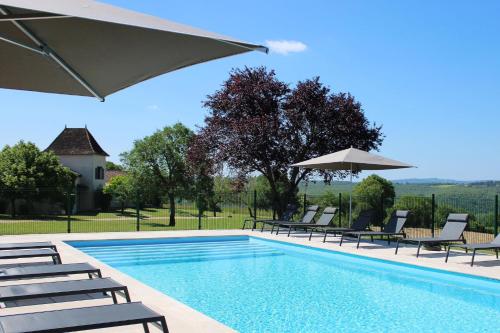 a swimming pool with lounge chairs and an umbrella at H&ocirc;tel Les Vieilles Tours Rocamadour in Rocamadour