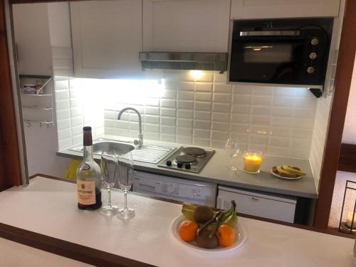 - une bouteille de vin et un bol de fruits sur un comptoir de cuisine dans l'établissement Appartement idéalement situé, à Arzon
