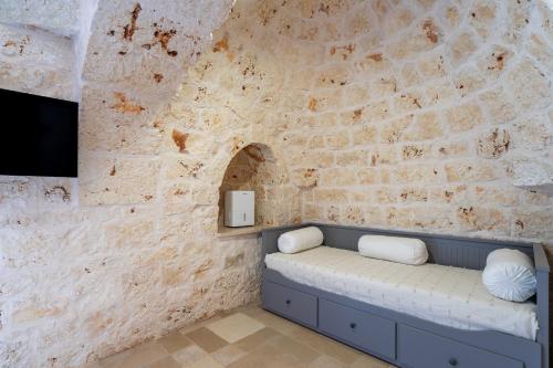 a stone wall with a bench in front of a tv at Tenuta di Uma by Perle di Puglia in Carovigno