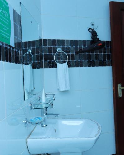 a bathroom with a sink and a mirror at Mowicribs Hotel and Spa in Entebbe