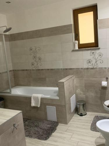 een badkamer met een bad, een wastafel en een spiegel bij REDhouse in Baia Mare