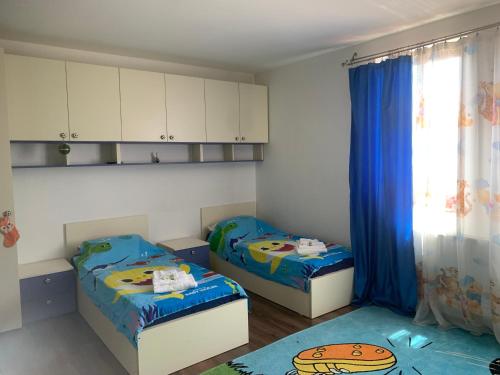 twee bedden in een kleine kamer met blauwe gordijnen bij REDhouse in Baia Mare
