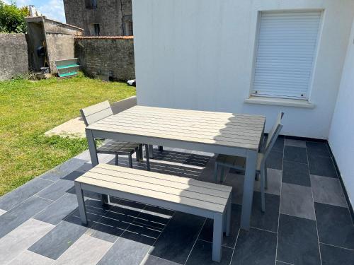 une table de pique-nique et deux bancs sur une terrasse dans l'établissement maison agréable et calme dans ile oleron, au Château-dʼOléron