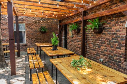 a patio with wooden tables and chairs and a brick wall at Gorgeous Gecko Guesthouse in Modimolle