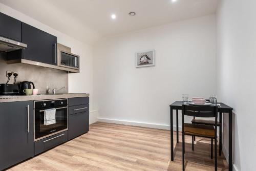 a kitchen with black cabinets and a table in it at Modern and Bright Studio in Central Sheffield in Sheffield