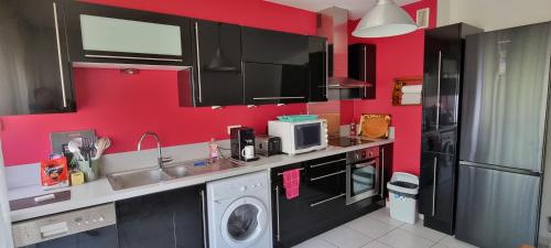 une cuisine aux murs rouges et un lave-linge/sèche-linge. dans l'établissement SPITIMOU BORDEAUX, à Cenon
