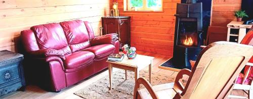 a living room with a leather couch and a stove at Le Ratbotté in Velosnes