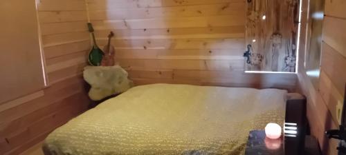 a bedroom with a bed in a room with wooden walls at Le Ratbotté in Velosnes