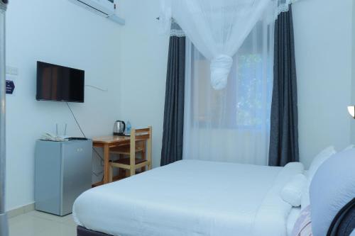 a bedroom with a white bed and a window at Mowicribs Hotel and Spa in Entebbe
