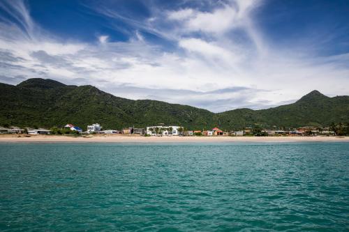a body of water with a beach and mountains in the background at iSea Resort in Ba Ha