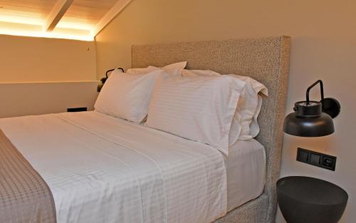 a bedroom with a bed with white sheets and pillows at Opuntia Boutique Hotel in Kalívia