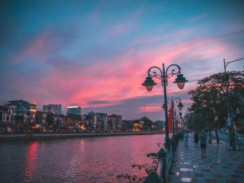 people walking on a sidewalk next to a river with a sunset at X-Stay in Hai Phong