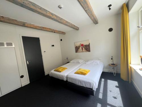 a bedroom with a bed with white sheets and yellow blankets at Art Hotel Harlingen in Harlingen